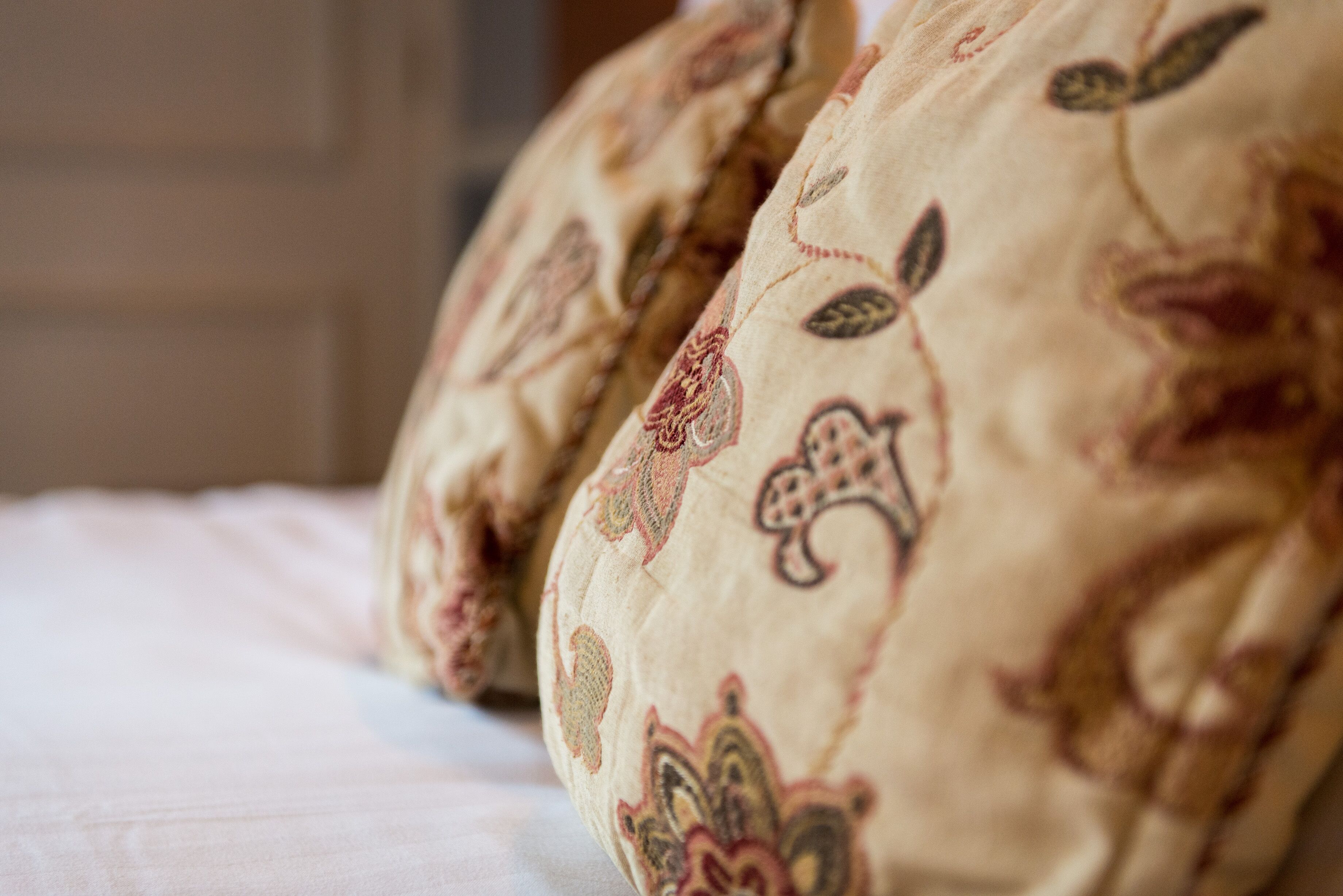 Primer plano de una cama con una manta estampada y almohadas.