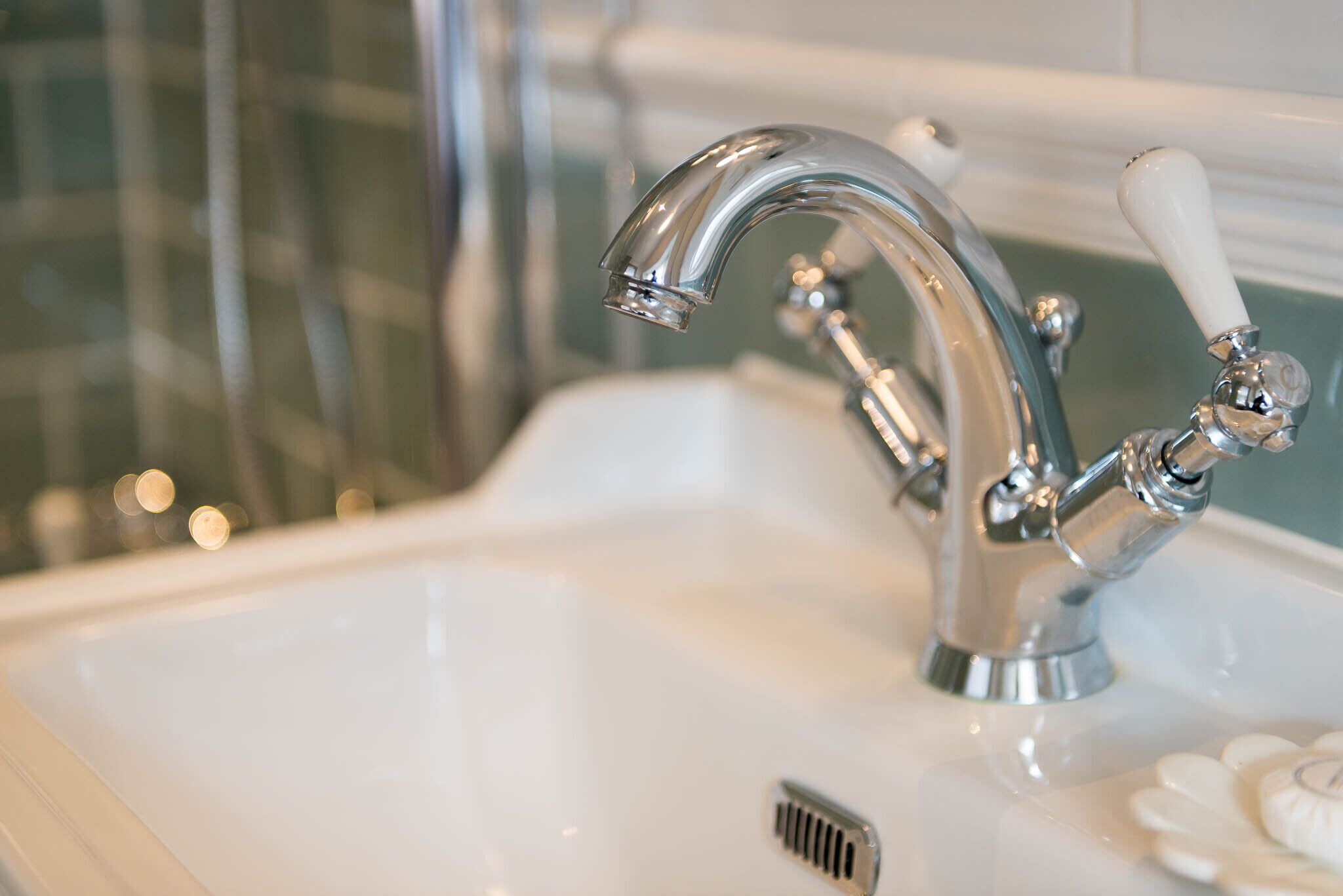 A bathroom sink with a chrome faucet and a white handle.