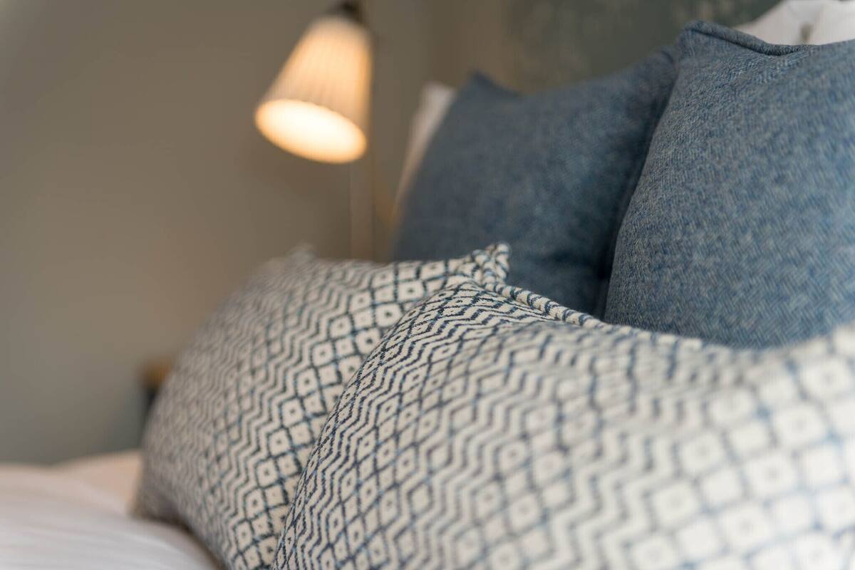 A bed with patterned pillows and a hanging light fixture.