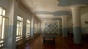 Una habitación amplia con suelo a cuadros, ventanas grandes y una mesa en el centro.