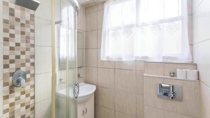A bathroom with a shower, toilet, sink, and window with curtains. - La Ballito Self Catering Apartment (Ballito)