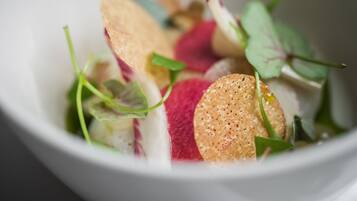 A bowl of salad with various vegetables and a cracker.