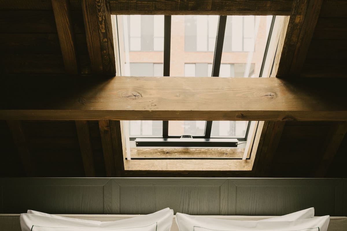 Una habitación con techo inclinado, tragaluz y cama con ropa de cama blanca.