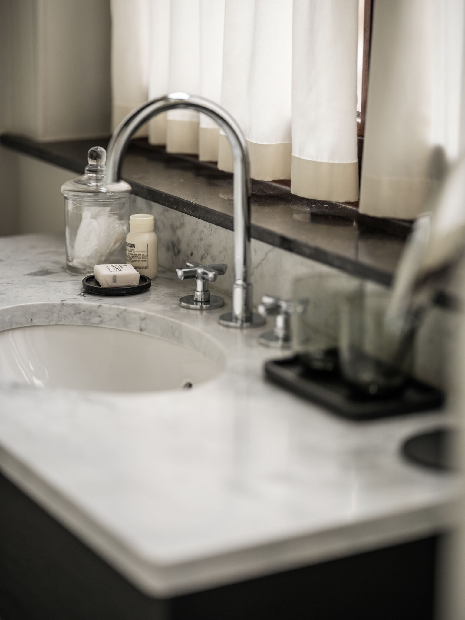 A bathroom sink with a mirror above it, a soap dispenser, and a glass jar.