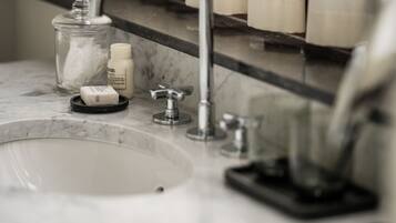 A bathroom sink with a mirror above it, a soap dispenser, and a glass jar.