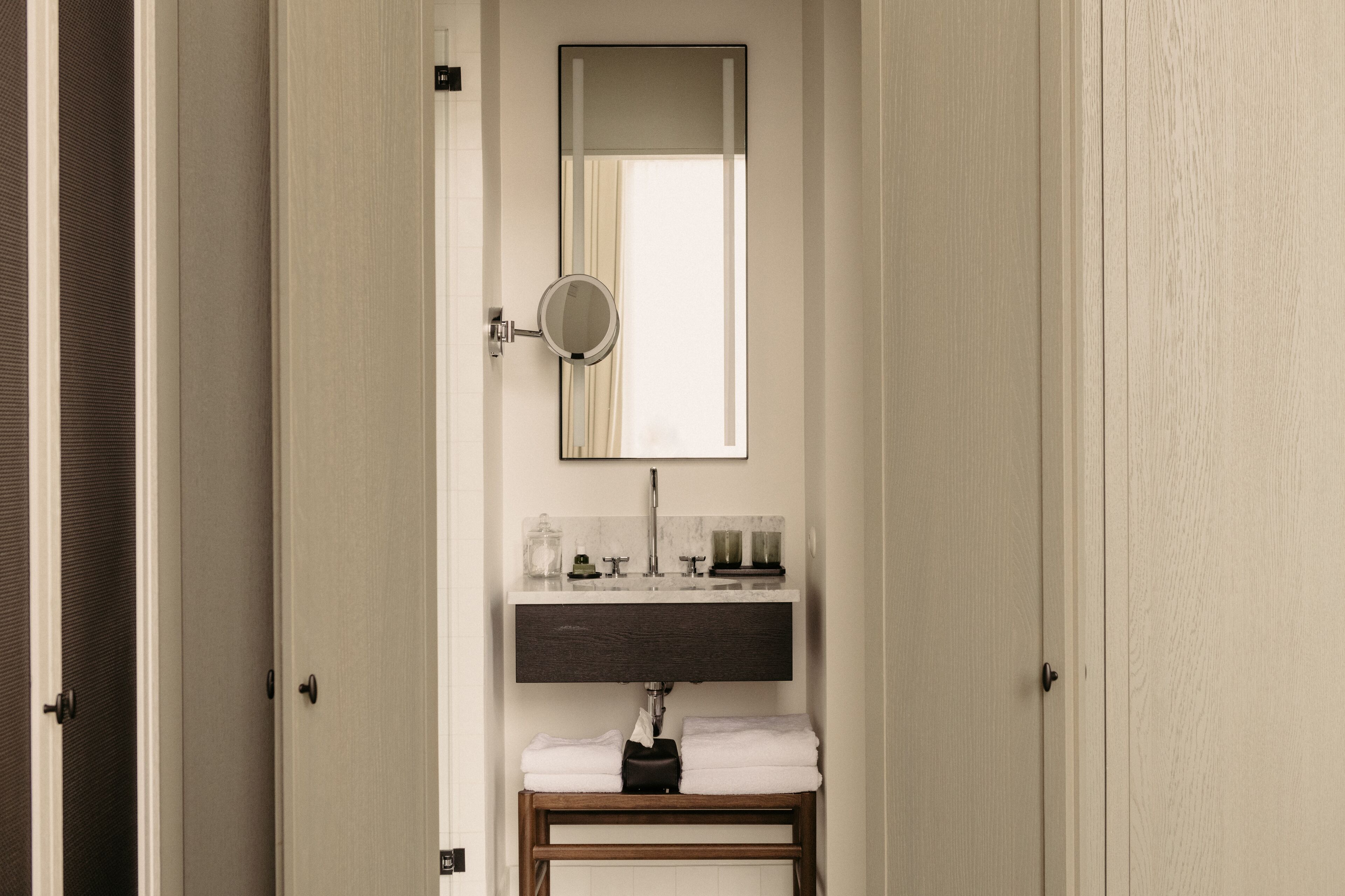 A bathroom with a mirror, sink, and towel rack.