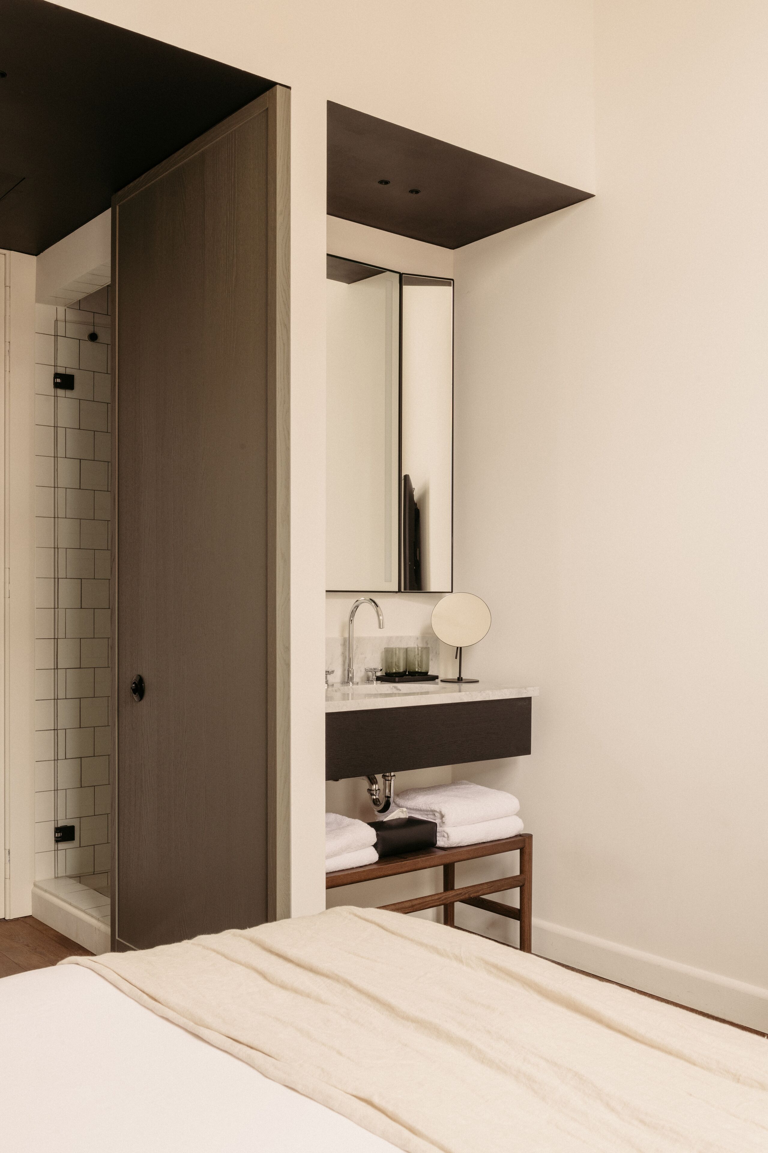 Un baño moderno con puerta de madera, un espejo y un lavamanos.