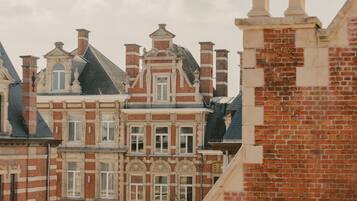A multi-story building with red brick facades and white window frames, featuring ornate architectural details and multiple chimneys.