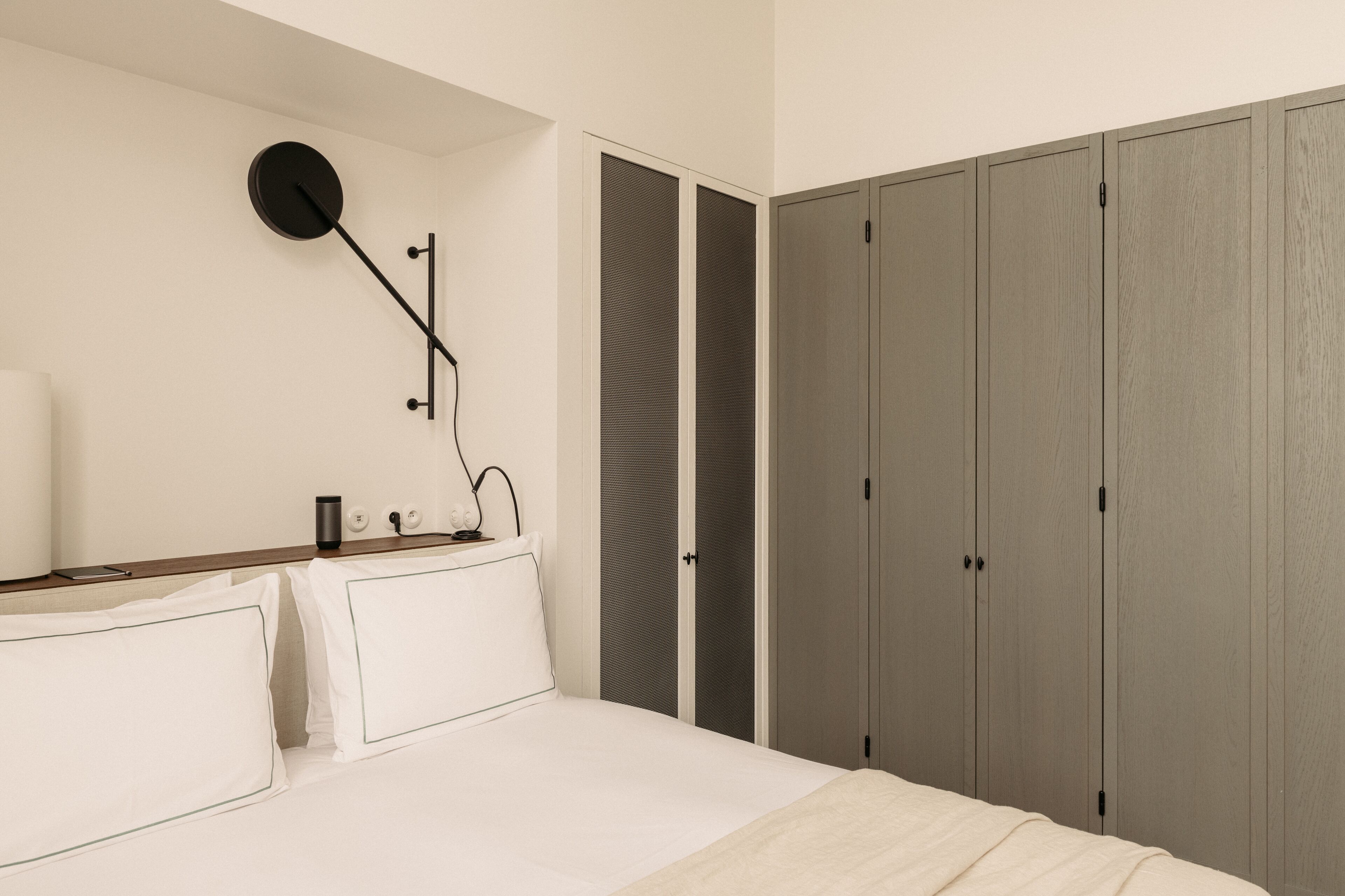A bedroom with a bed, bedside table, lamp, and wardrobe.
