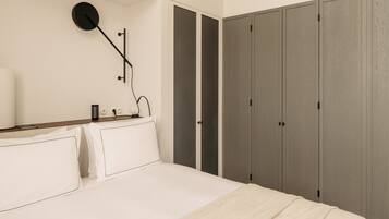 A bedroom with a bed, bedside table, lamp, and wardrobe.