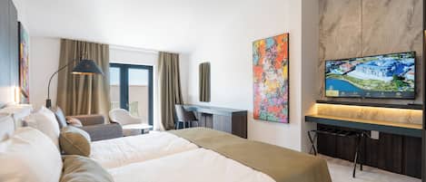 Habitación de hotel con cama, escritorio, televisión y obras de arte.