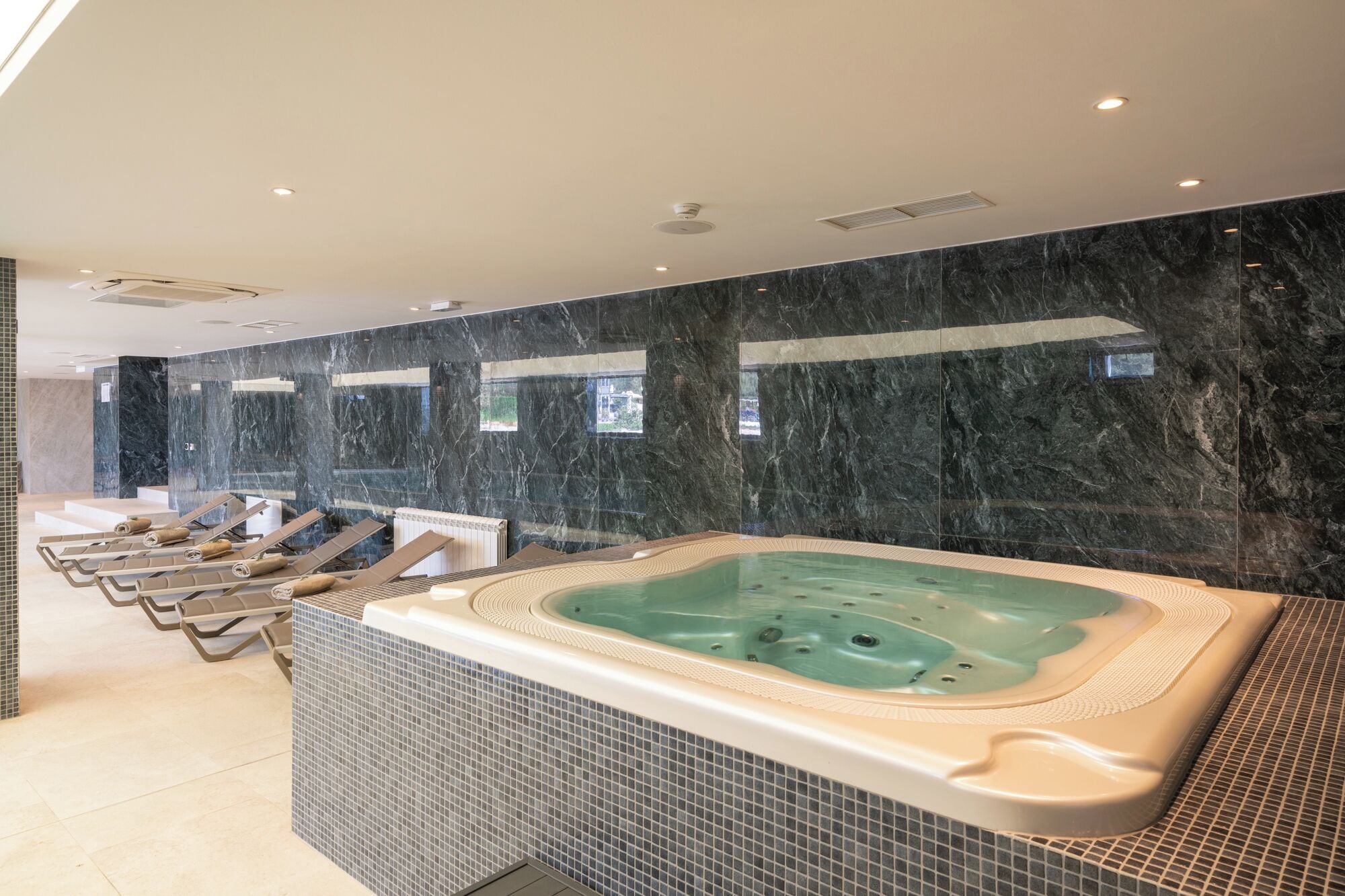 Un espace spa comprenant plusieurs bains à remous et des chaises longues.
