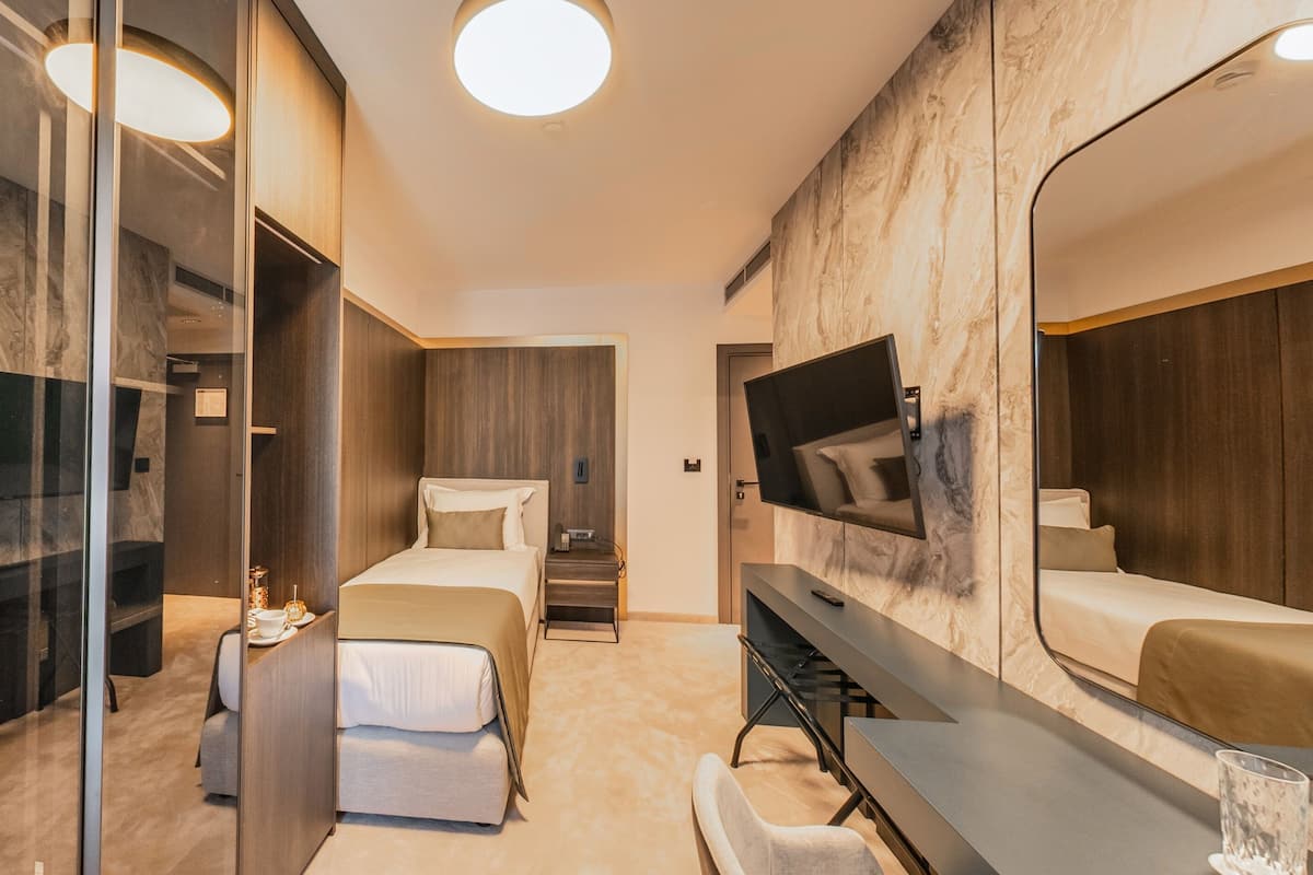A modern hotel room with a large bed, a desk, a TV, and a mirror.