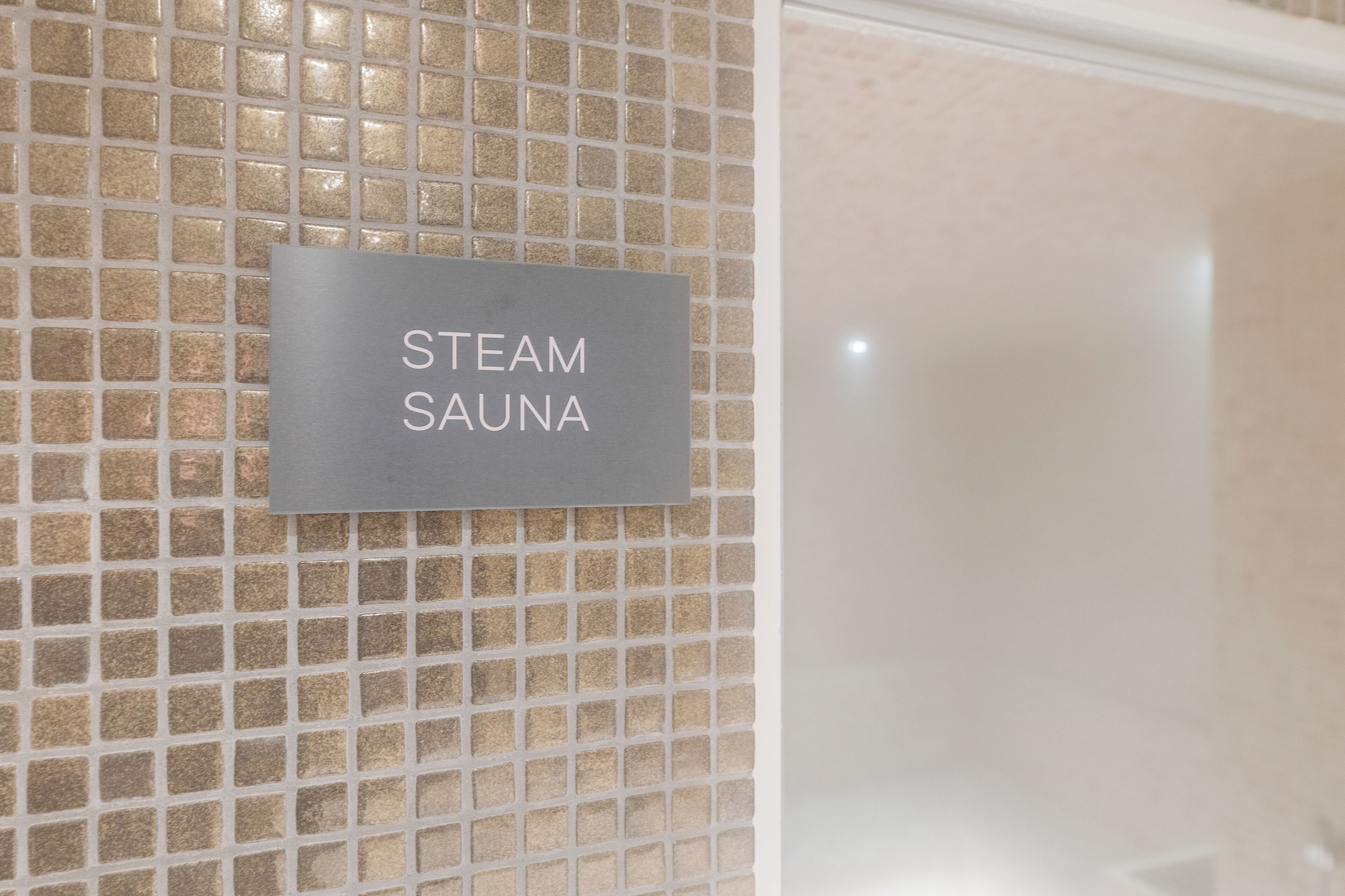 Una señal en una pared de azulejos que dice 'STEAM SAUNA'.