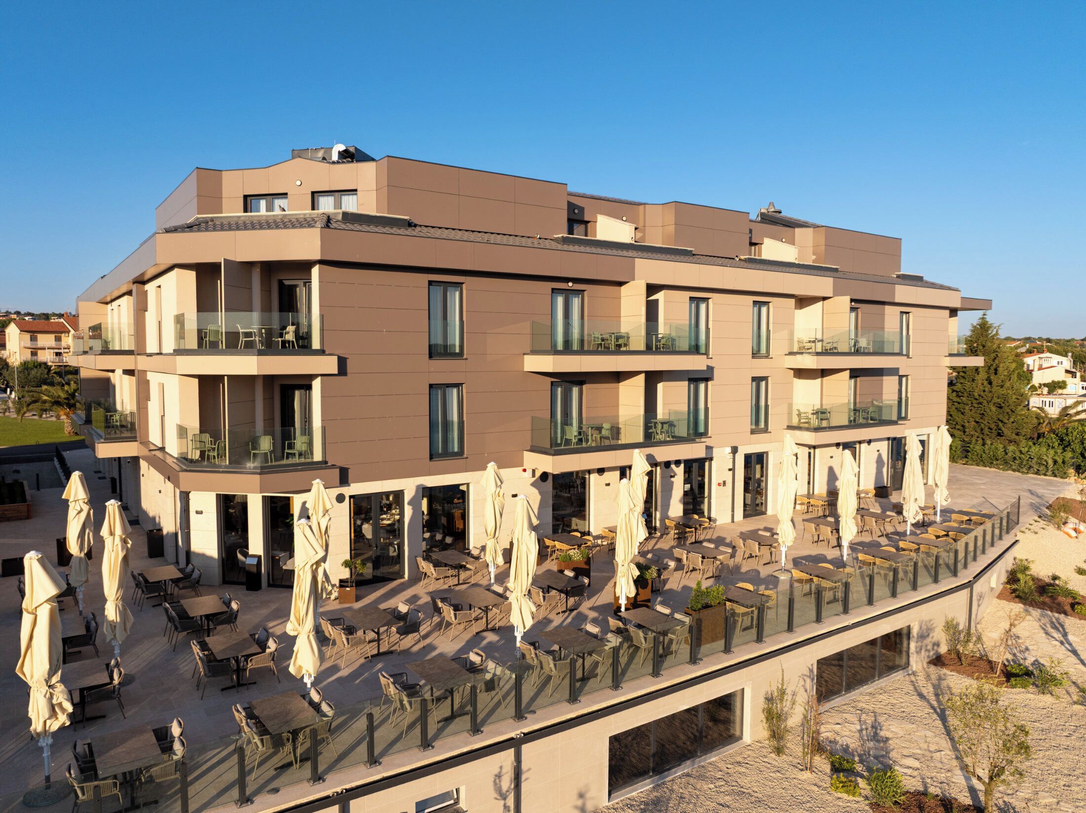 Een meerlaags hotel met buiten zitplaatsen en een overdekt terras.