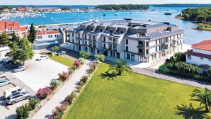 Un hotel moderno con un patio central, rodeado por un puerto deportivo lleno de barcos.