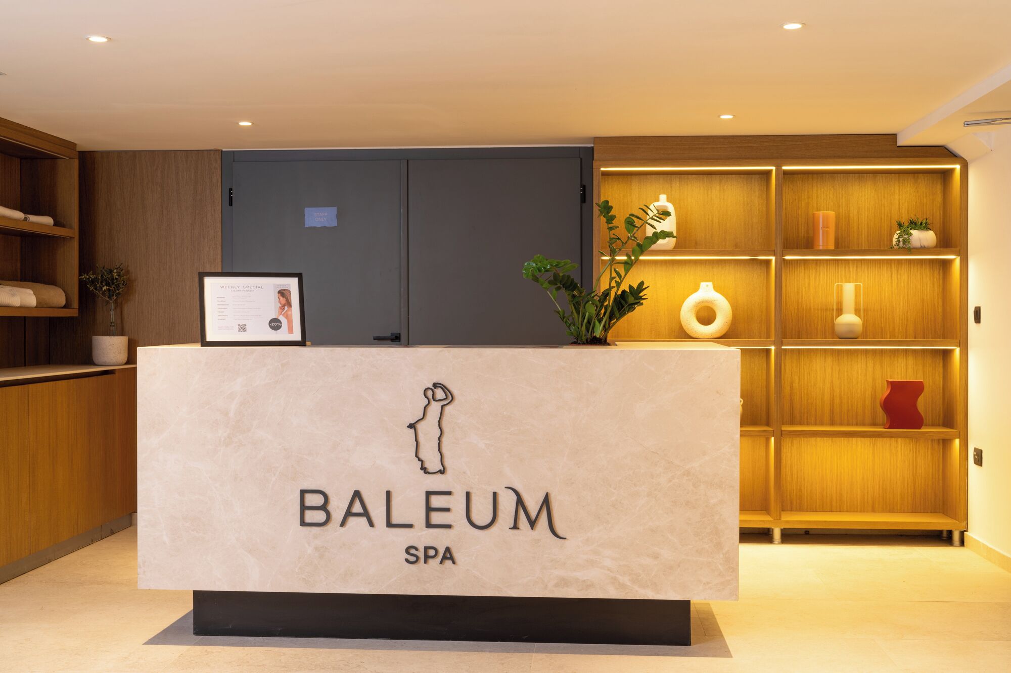 Een receptiebalie met een bord waarop 'BALEUM SPA' staat en een inlijsting met een certificaat.