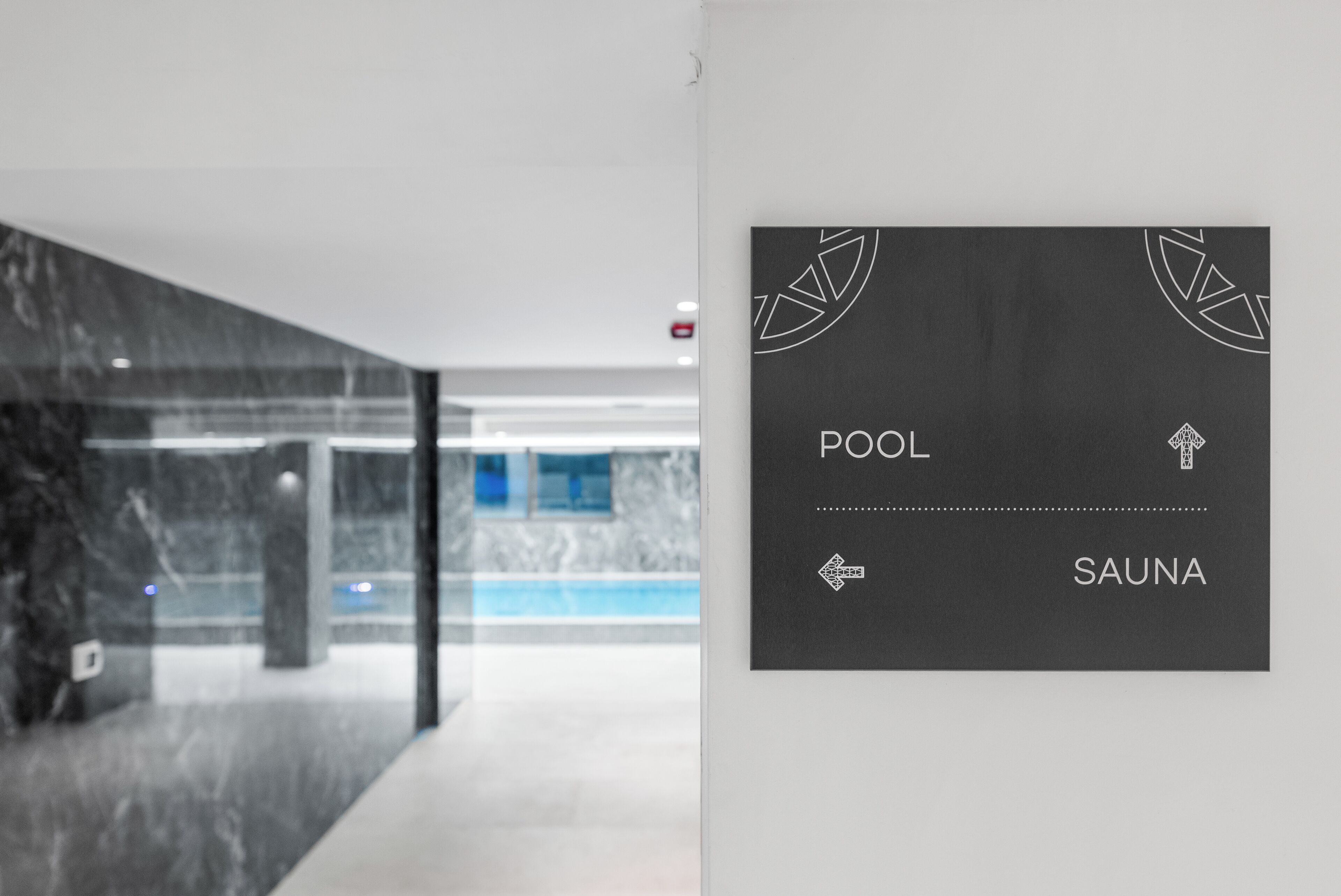 A modern interior with a sign indicating a pool and sauna.