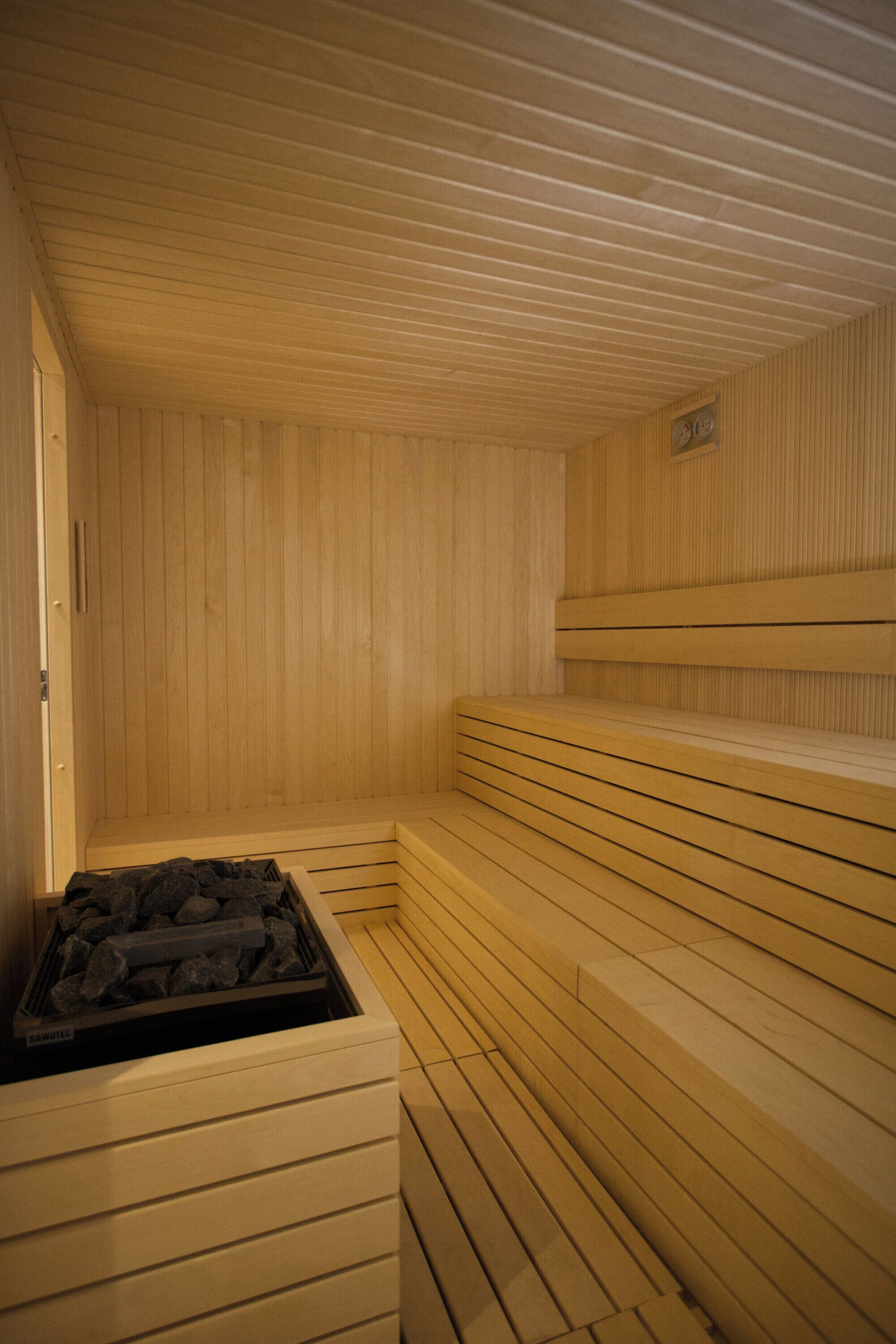 A sauna with wooden benches and a charcoal stove.