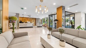 Un moderno vestíbulo de hotel con una recepción, zona de estar y ventanas amplias.