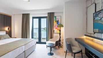 Une chambre d’hôtel moderne, dotée d’un grand lit, d’un bureau, d’une chaise, d’une lampe de bureau et d’un tableau au mur.