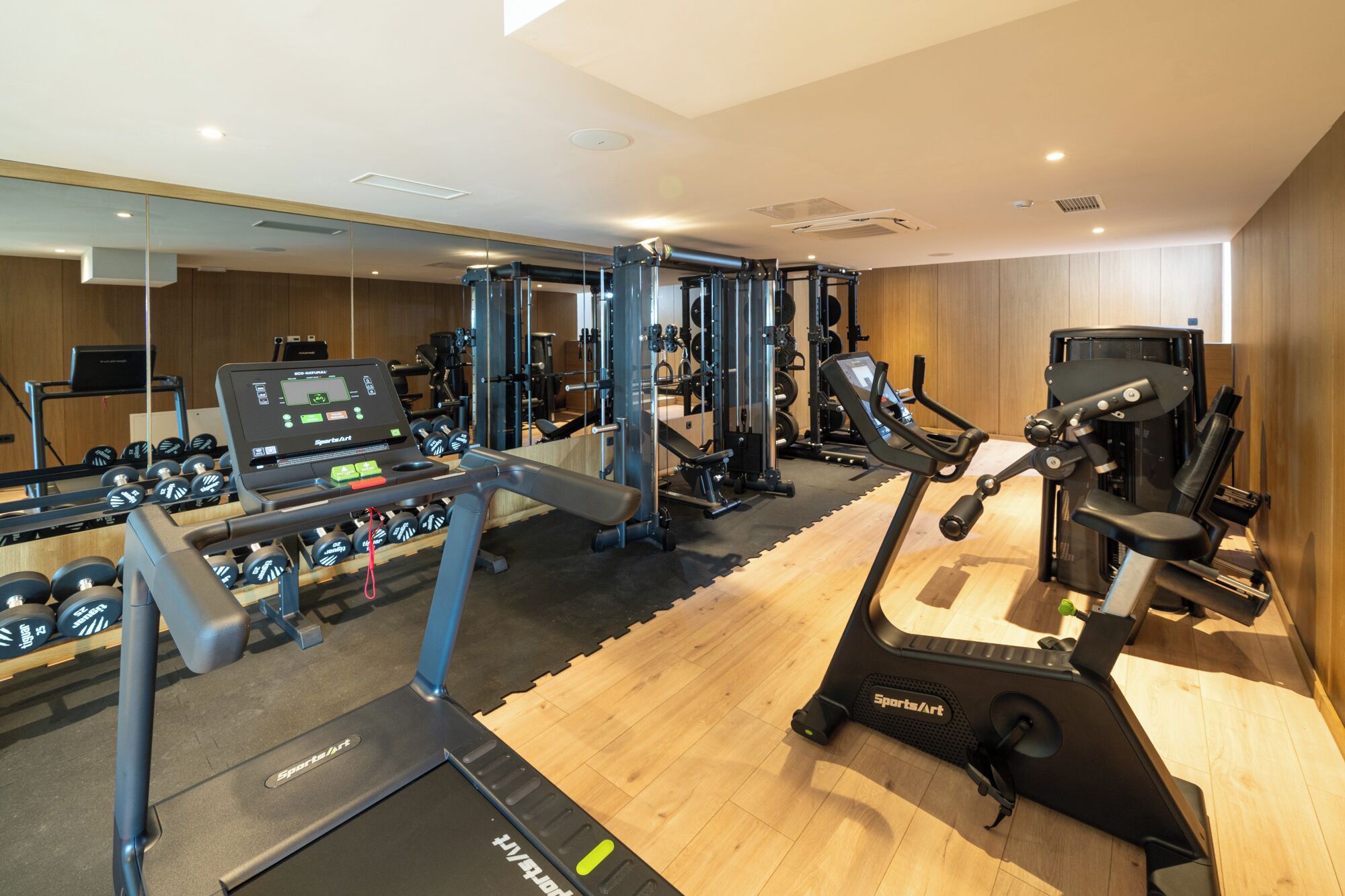 A gym with cardio equipment, weight machines, and dumbbells.