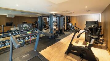 A gym with cardio equipment, weight machines, and dumbbells.