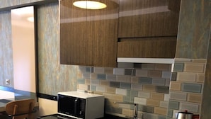 Una cocina compacta con armarios de madera oscura, un microondas, un fregadero y una tetera.