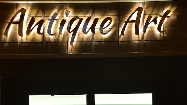 Un escaparate con letreros iluminados que dicen "Antique Art".