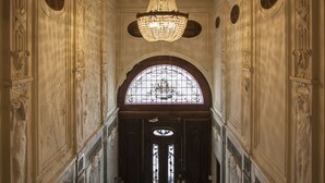 Un vaste hall d’entrée orné de sculptures complexes sur les murs, surmonté d’un grand lustre et doté d’une imposante porte en arc de cercle.