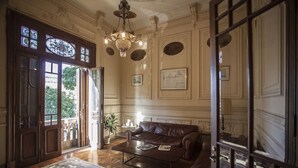 Une pièce spacieuse avec une grande porte en bois, un canapé en cuir marron, une table basse et un lustre.