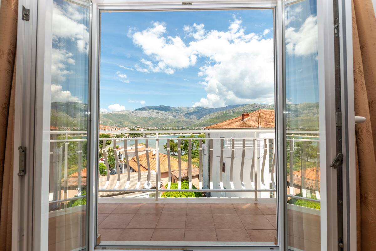 A balcony with a clear view of the surrounding landscape, including mountains and buildings.