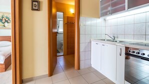 Una cocina con gabinetes blancos, estufa de acero inoxidable y salpicadero de azulejos.