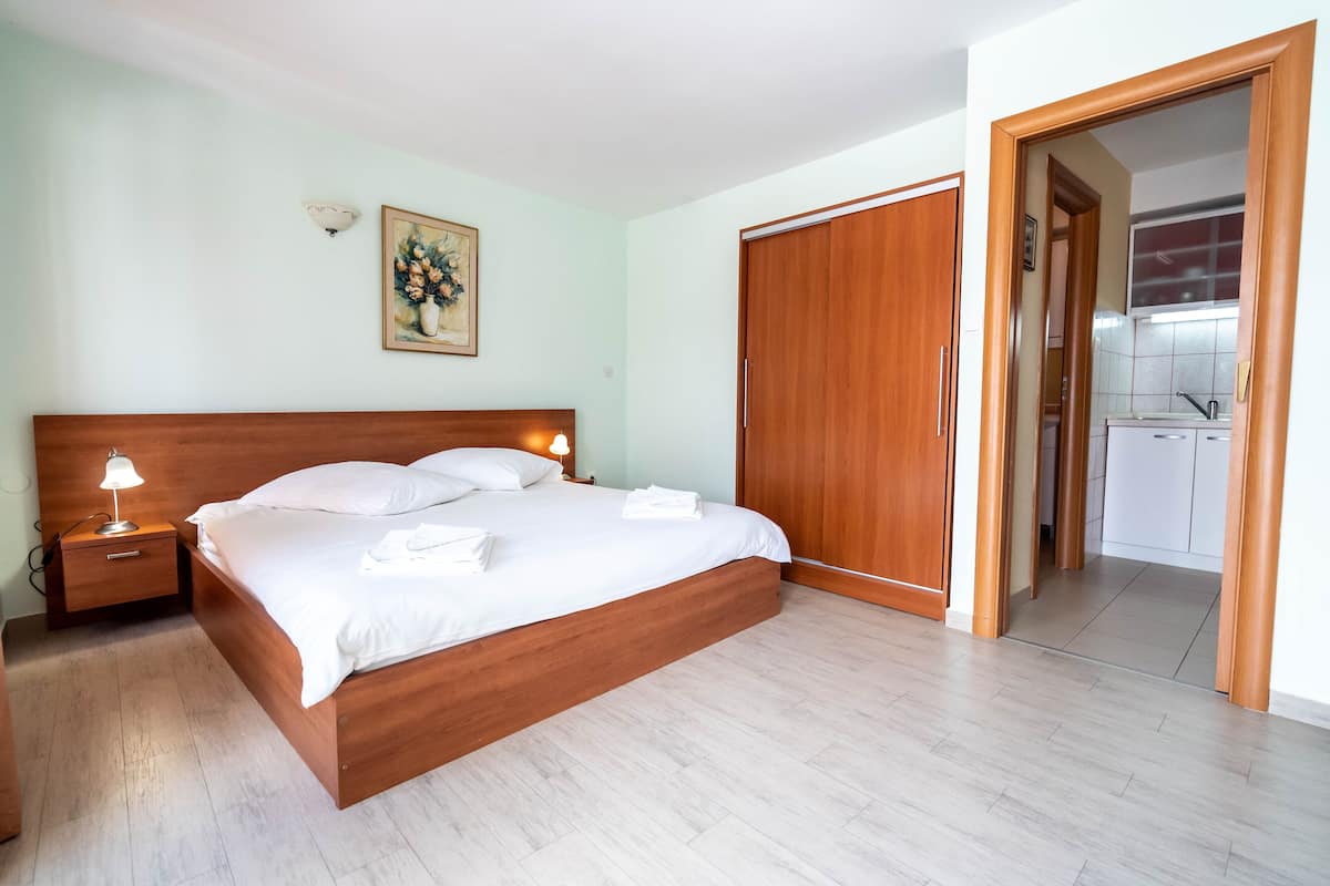 A bedroom with a wooden bed, bedside lamps, a painting on the wall, and a wooden wardrobe.