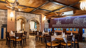 Un restaurante con paredes de piedra, vigas de madera en el techo y mesas dispuestas para comer.