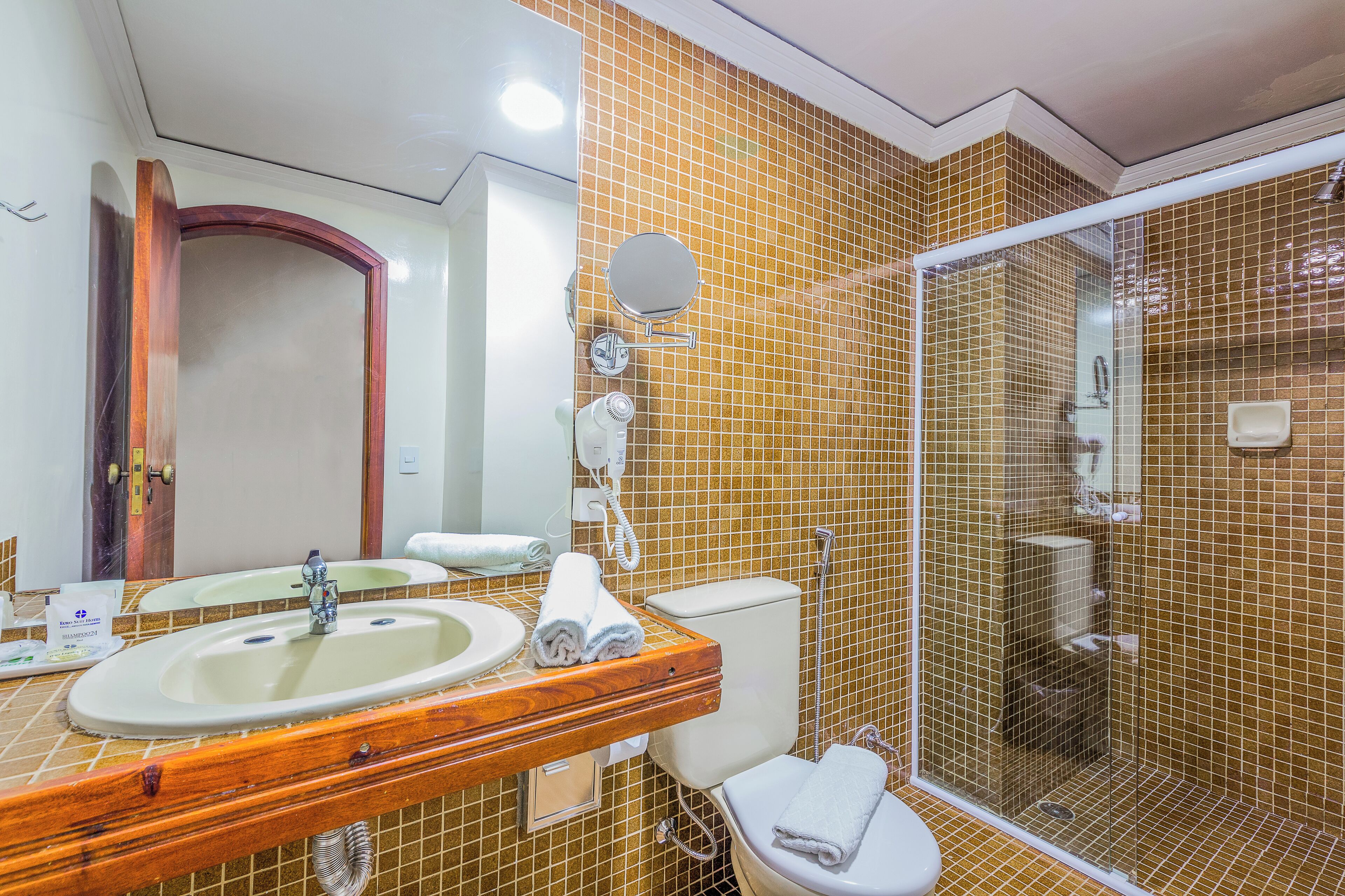 A bathroom with a wooden vanity, a sink, a toilet, and a glass-enclosed shower.