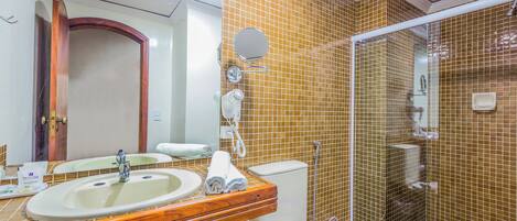 A bathroom with a wooden vanity, a sink, a toilet, and a glass-enclosed shower.