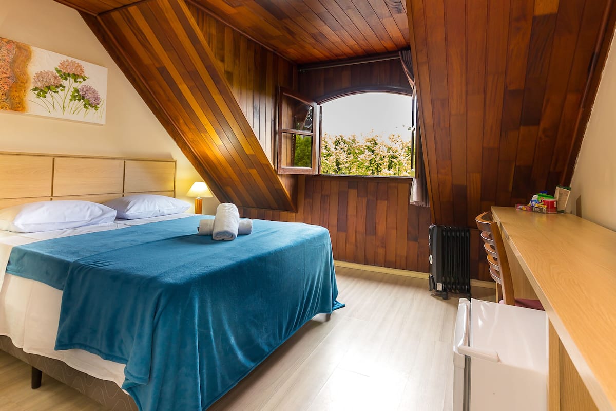 Un dormitorio con cama, escritorio y ventana con vista a zonas verdes.