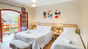 A hotel room with two beds, a wooden floor, a window with a view of a garden, and a bookshelf. - Hotel Euro Suite Campos do Jordão (Campos do Jordão)