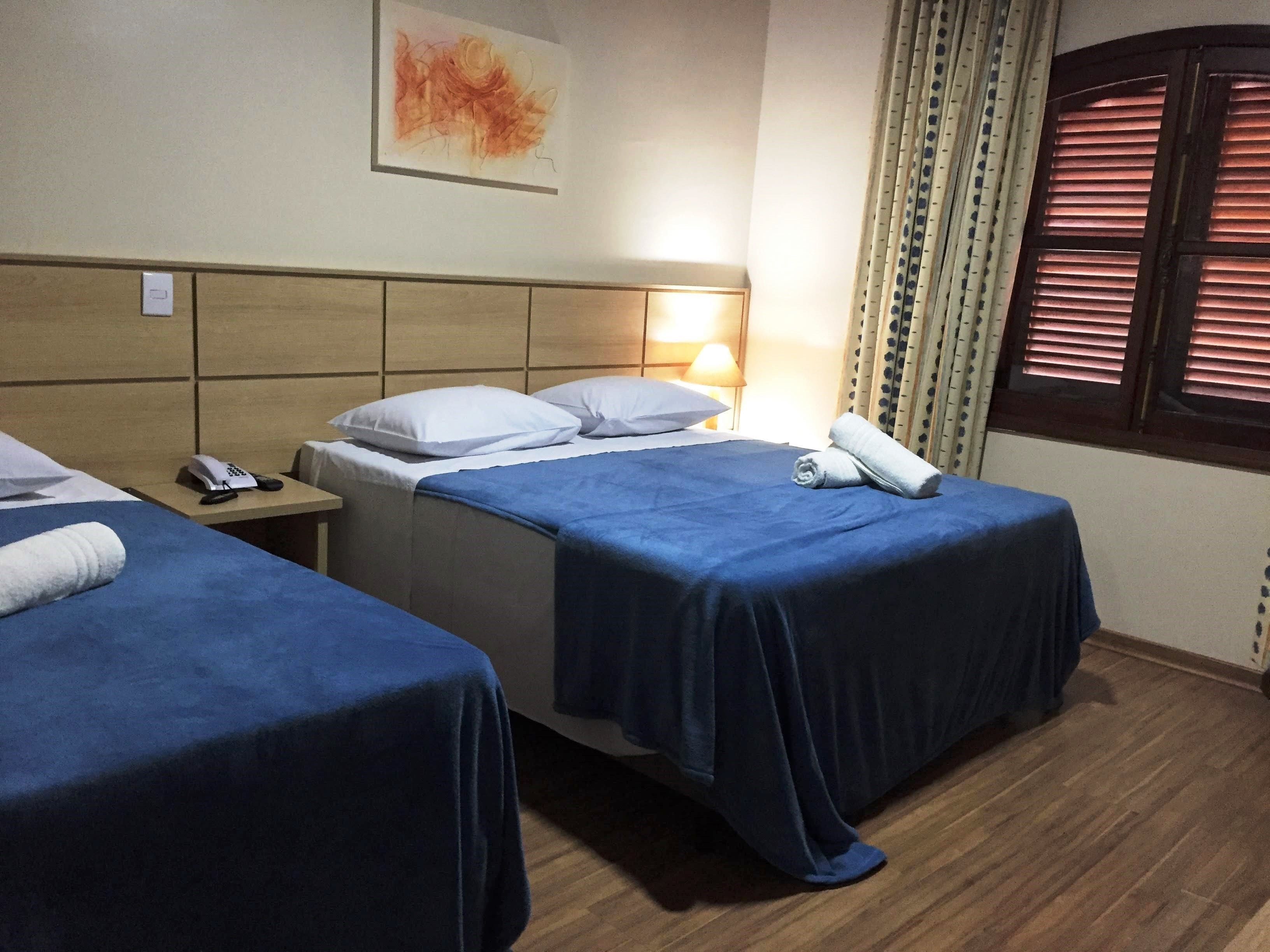 Habitación de hotel con dos camas, un teléfono junto a la cama y una lámpara.