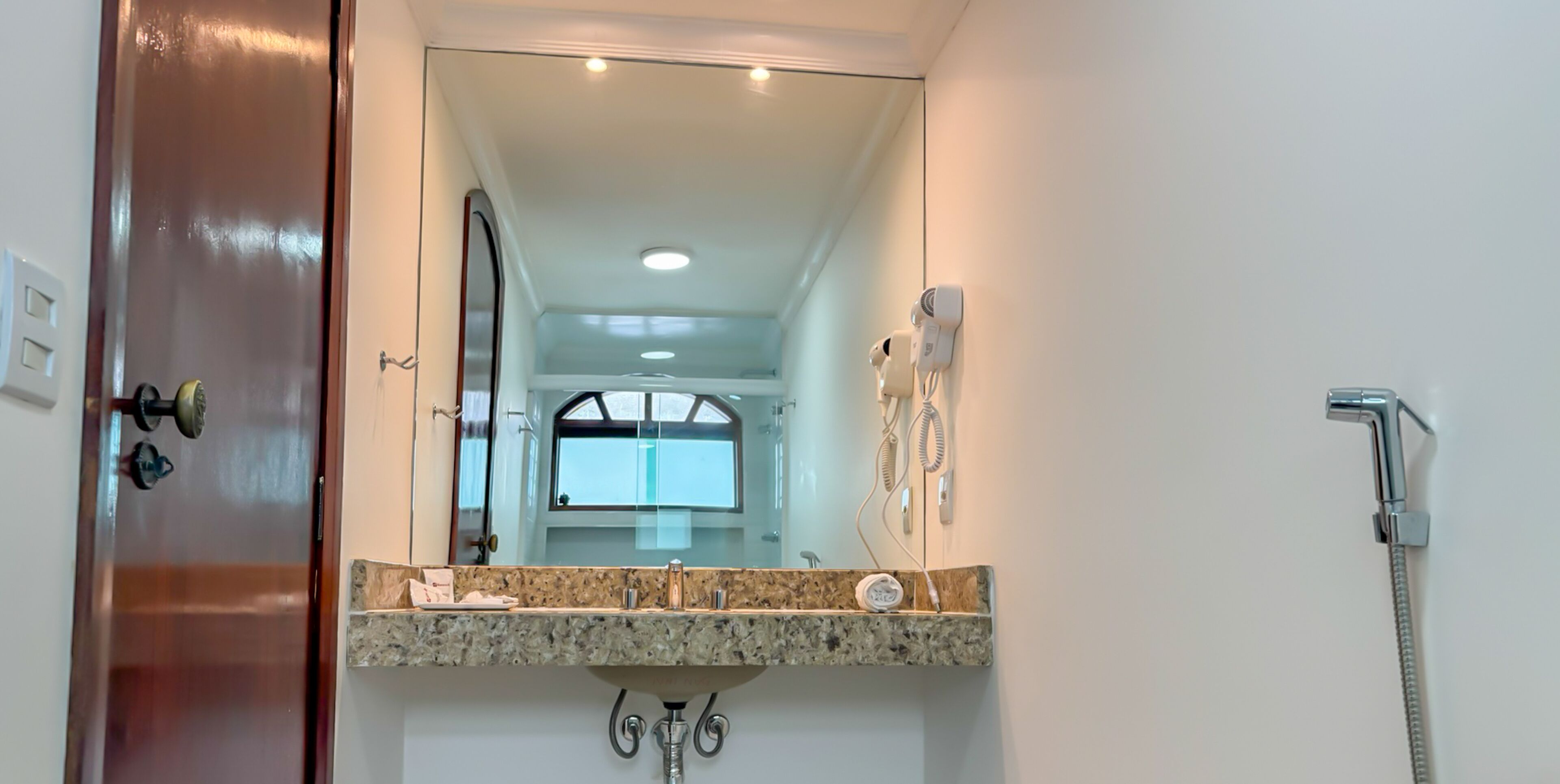 A bathroom with a granite countertop, a sink, a mirror, a shower, and a towel rack.