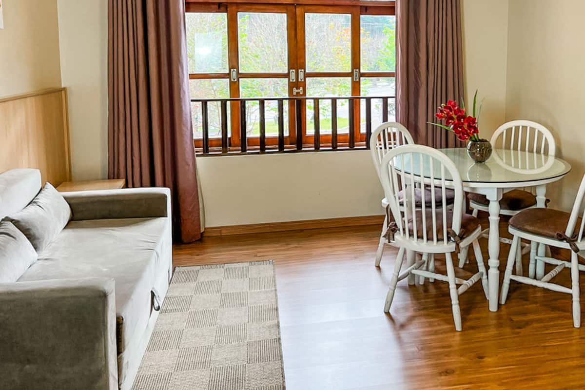 Una habitación acogedora con sofá, una mesa de comedor con sillas y una ventana con cortinas.