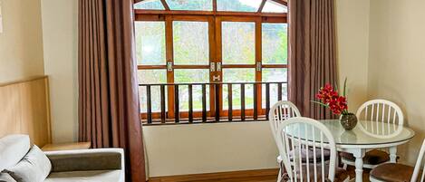 Una habitación acogedora con sofá, una mesa de comedor con sillas y una ventana con cortinas.