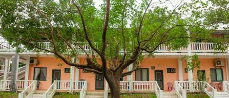 A building with a tree in front, white railings, and steps leading to the entrance.