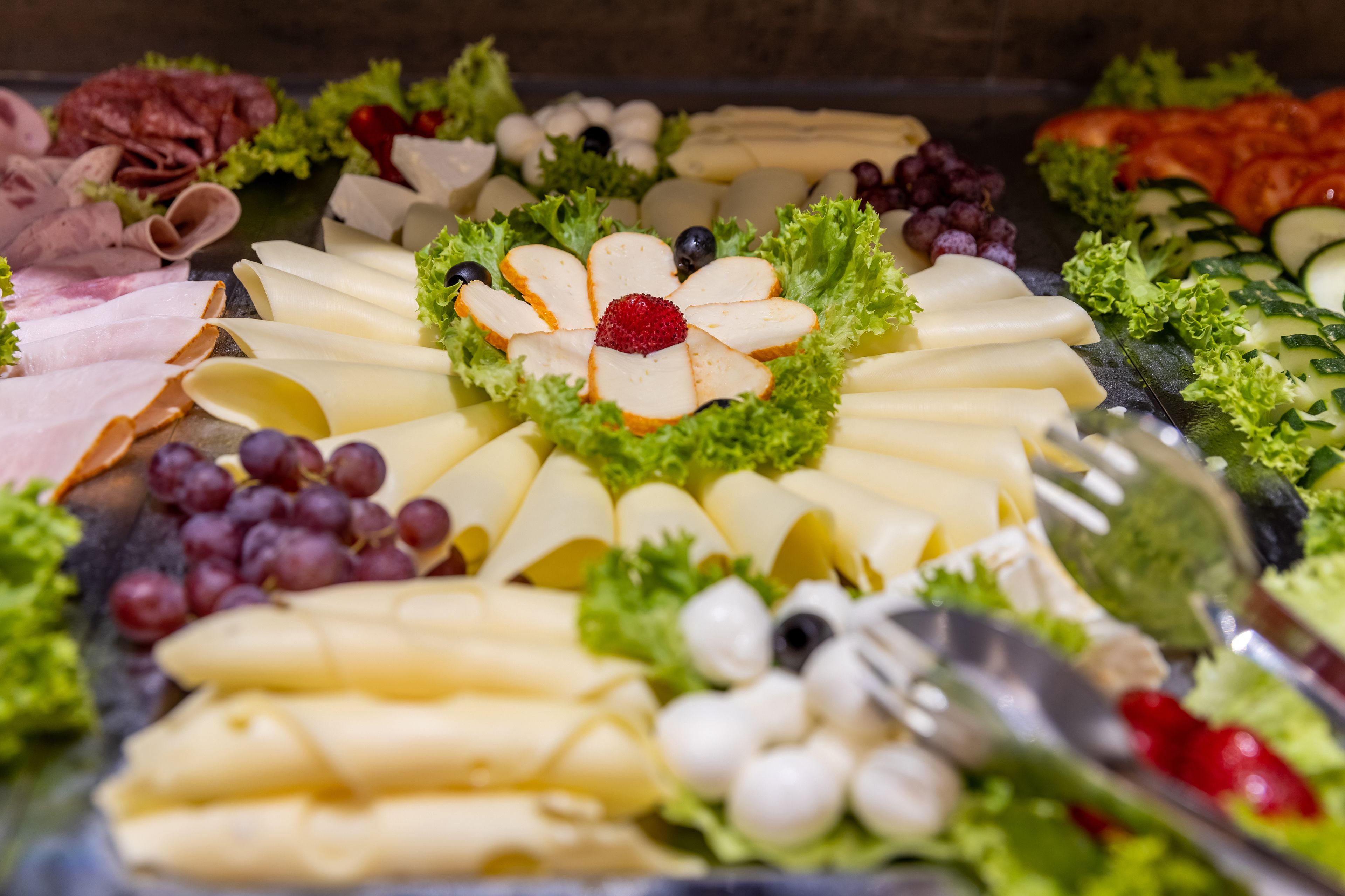 A variety of cheeses, fruits, and meats arranged on a platter.