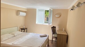 A bedroom with a bed, a desk, a chair, a window, and an air conditioning unit. - Green House (Kutaisi)
