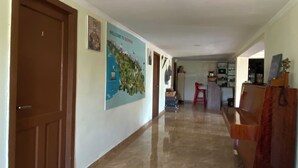 A hallway with a marble floor, a brown door, a welcome sign, and a wooden cabinet. - Green House (Kutaisi)