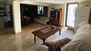 A spacious living room with a fireplace, a dining area, and a kitchen visible in the background. - Green House (Kutaisi)