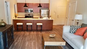 A modern kitchen with a central island, bar stools, and stainless steel appliances. - The Hamlet (Saratoga Springs)