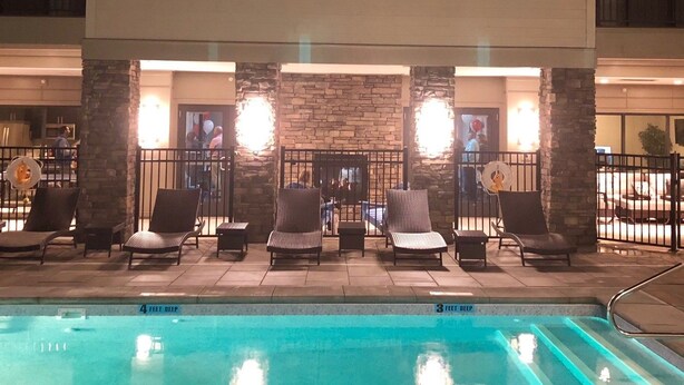 A poolside area with lounge chairs and a stone wall. - The Hamlet (Saratoga Springs)